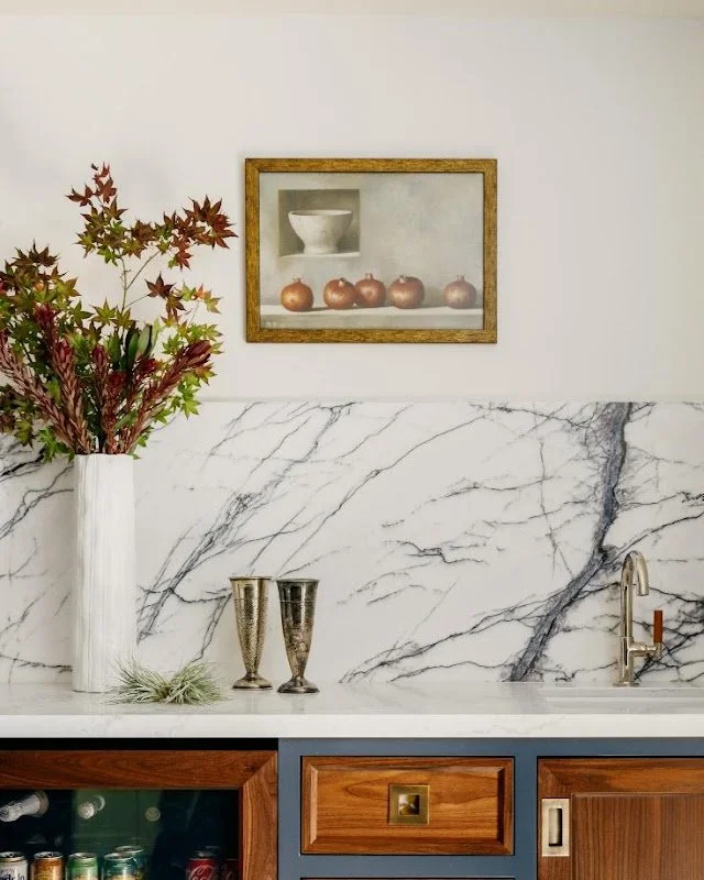 Styled marble mantel with framed artwork and autumn branches