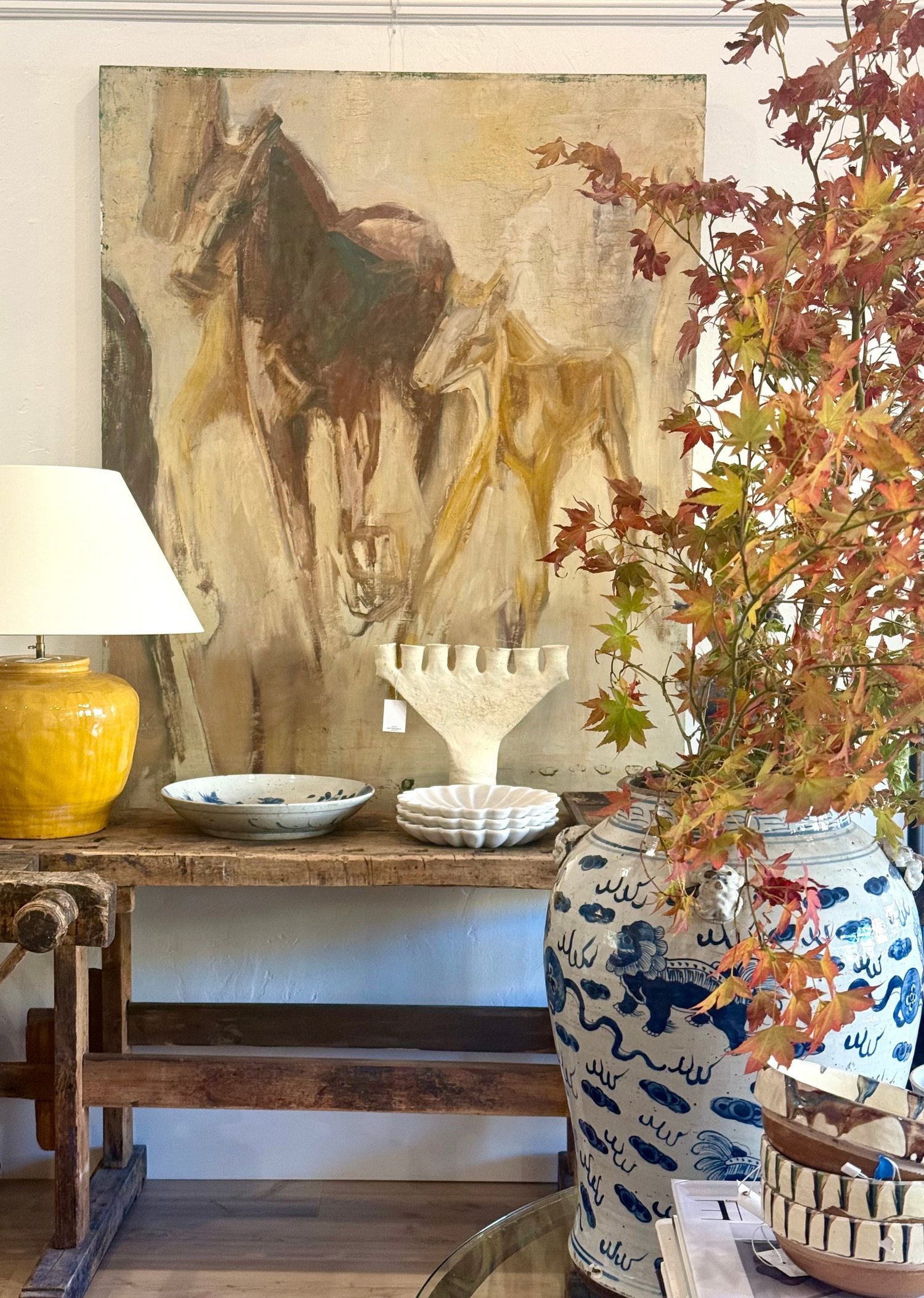 Tama Bell Design showroom console with equestrian painting and blue-and-white vase