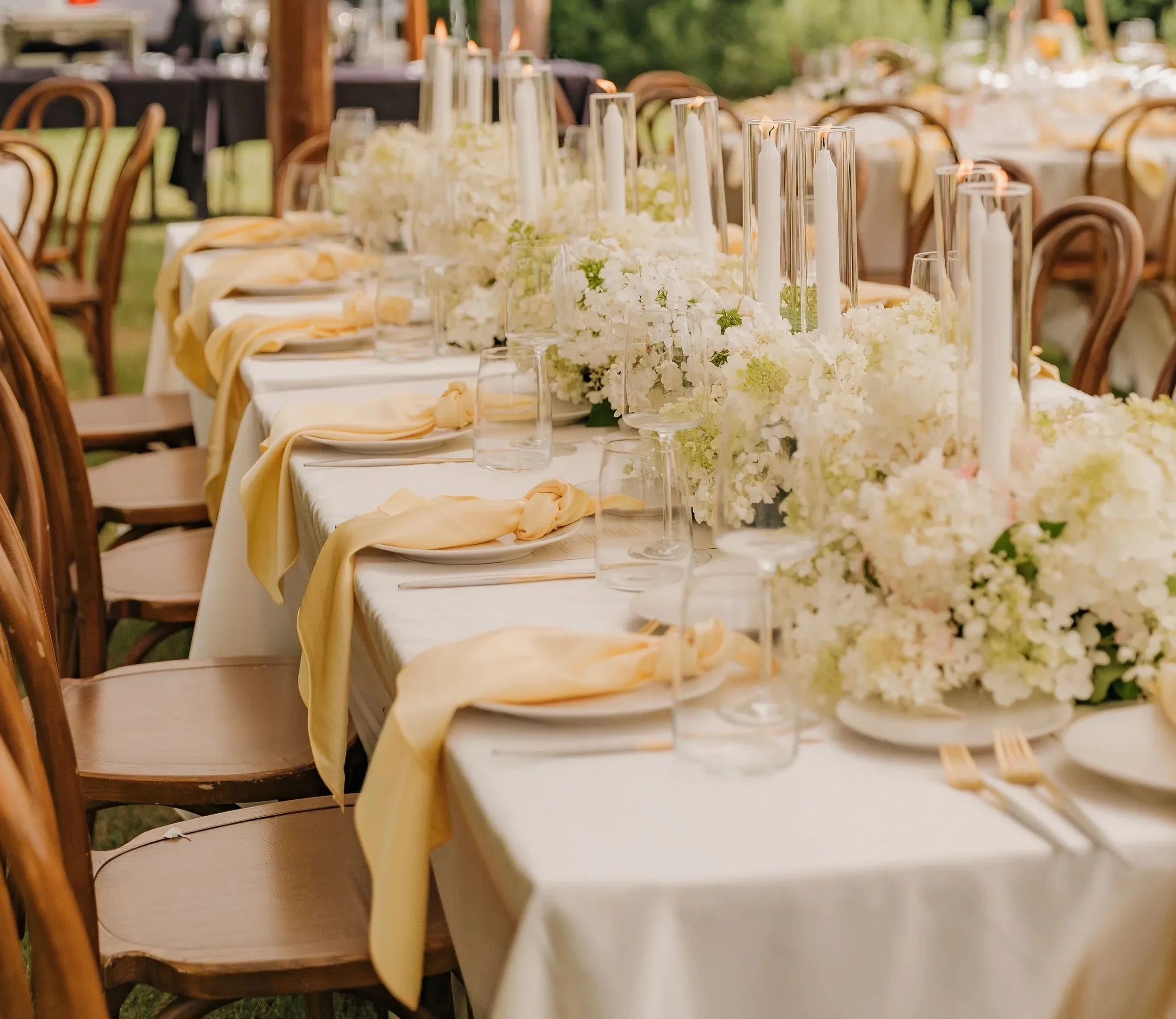A reception table with white flowers, candles and pale linens, featured by Fater Fairytale Weddings