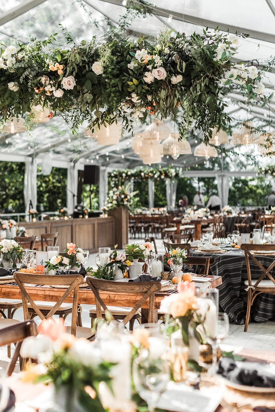 Flower-filled reception beneath a clear tent, supplied by Blue Fancy Events