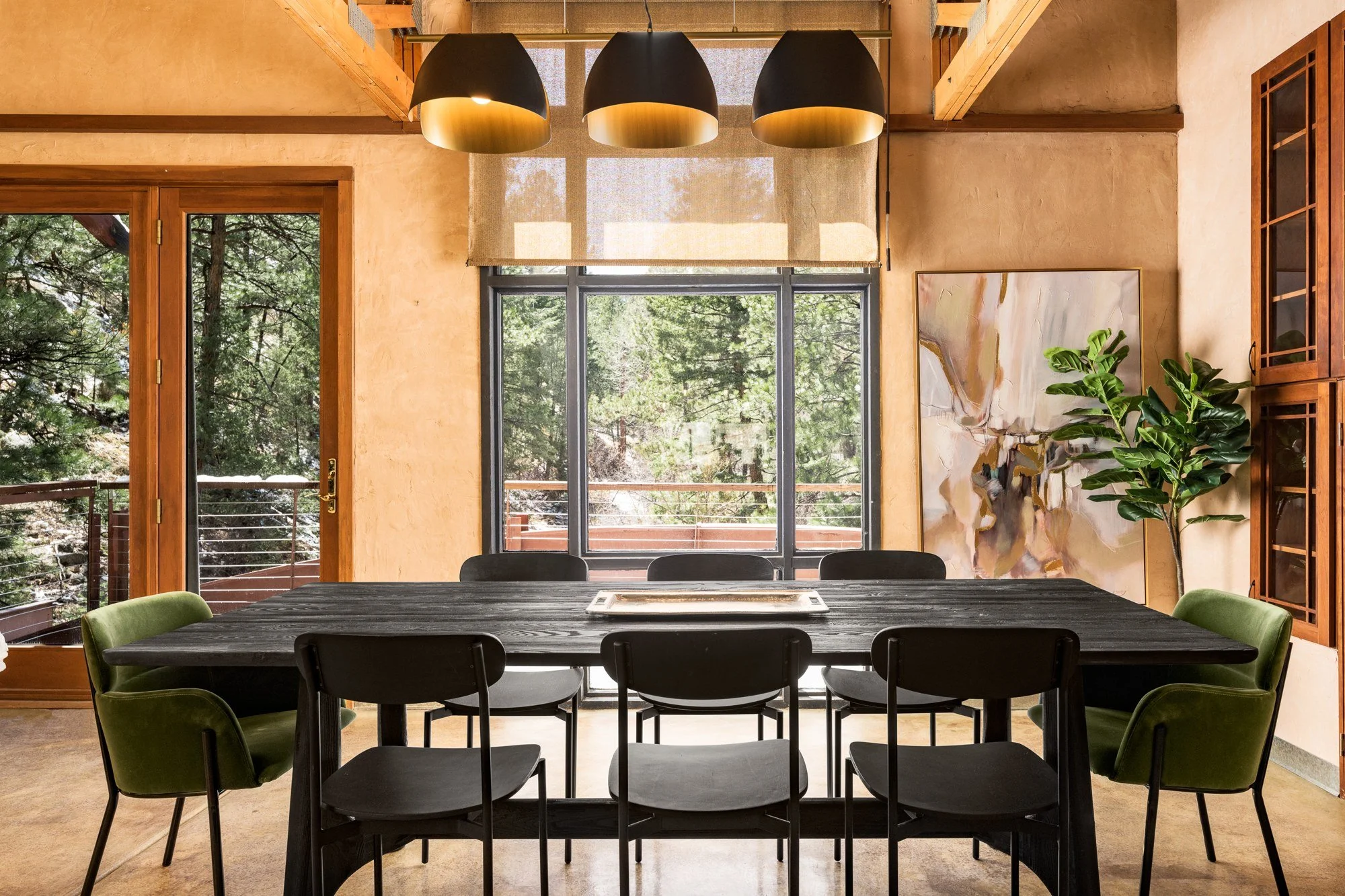 The Bridge House dining room with green chairs, timber beams and woodland views