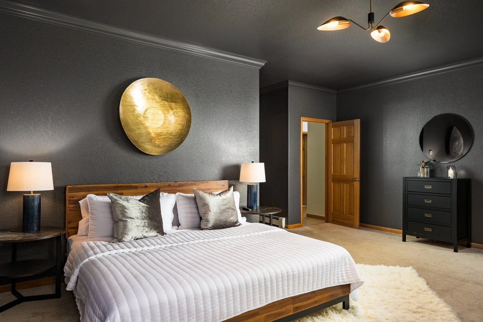 WonderLodge bedroom with a dark feature wall, round gold artwork and white bedding