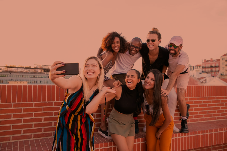 Group of young professionals in casual attire taking a selfie photo next to a brick wall