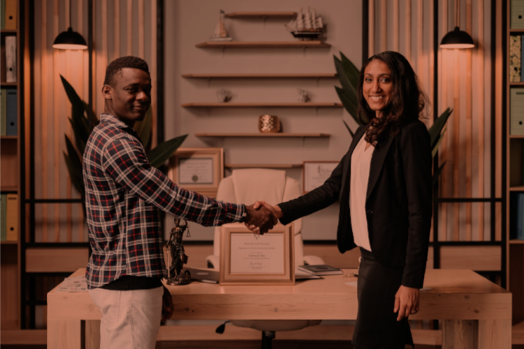 Two young professionals (one male, one female) shaking hands and smiling