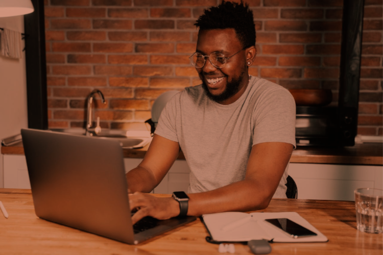 A young male profession working from home with laptop on a kitchen counter