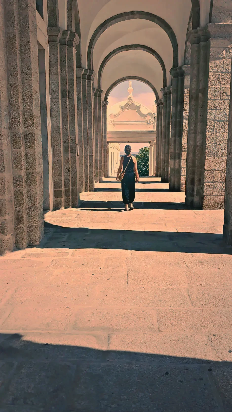 Jennie Lowes walking down a stone arcade towards the light
