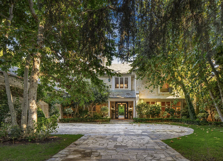 Ivy-covered traditional home behind a stone motor court and mature trees
