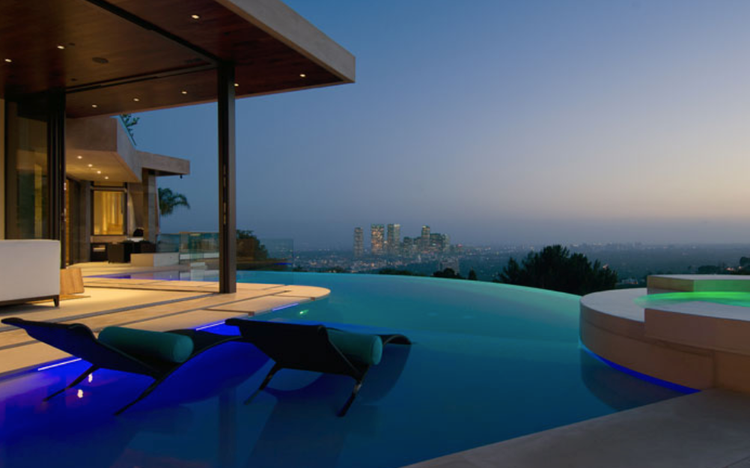 Infinity pool at night with city lights on the horizon