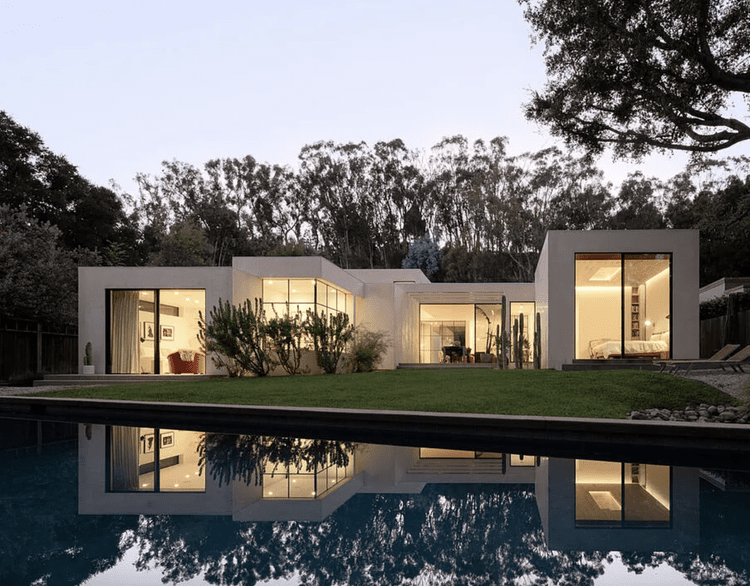 Minimalist white single-story modern reflected in a still pool at twilight