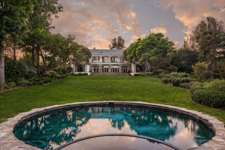 Classic estate with expansive lawn and round pool at dusk