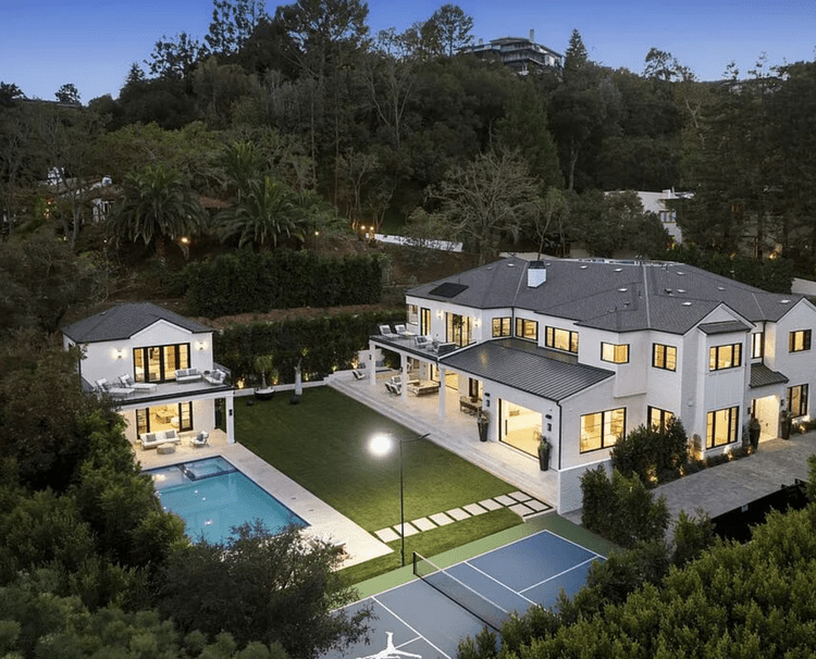 Aerial of a white two-story home with pool and sport court at night