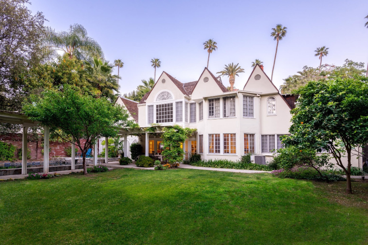White Tudor-style home with lawn and palm trees