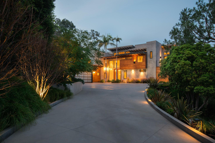 Wood-and-glass modern at the end of a lit driveway at twilight