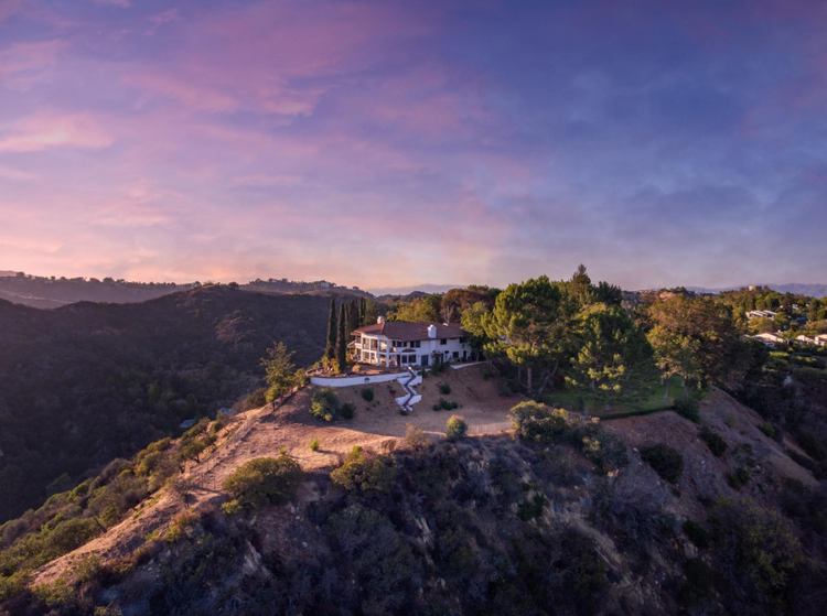 Aerial of a hilltop estate at sunset with canyon views