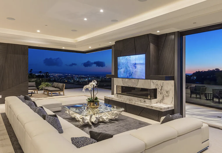 Living room with stone fireplace opening to a city-lights view