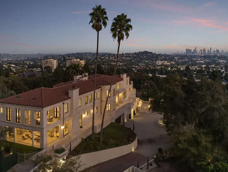 Spanish-style estate with red tile roof overlooking the city at dusk