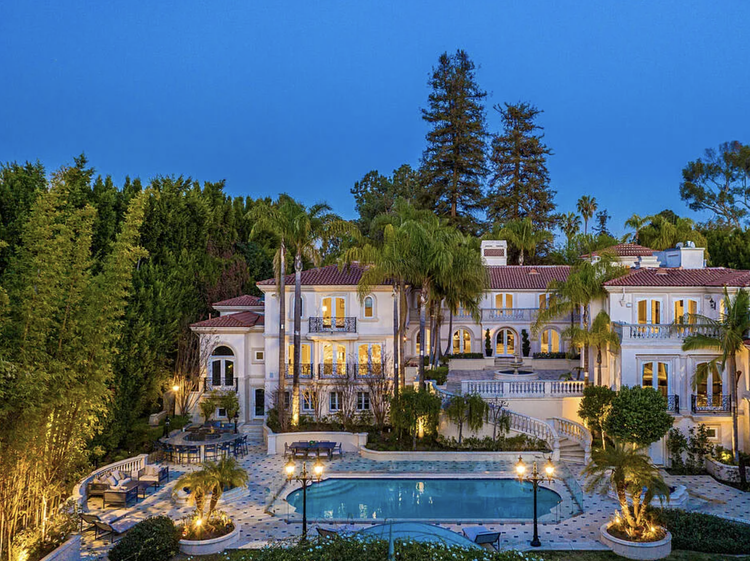 Grand Mediterranean villa lit at dusk, framed by palms