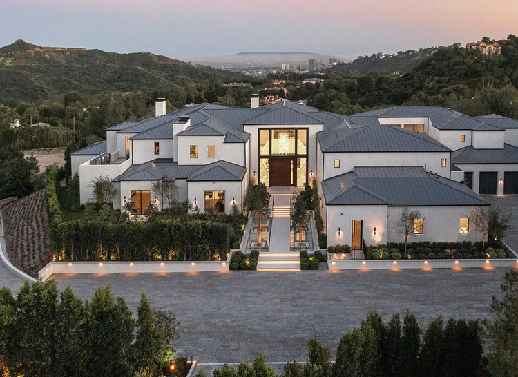 Modern farmhouse-style estate with gray roofs in the hills at dusk