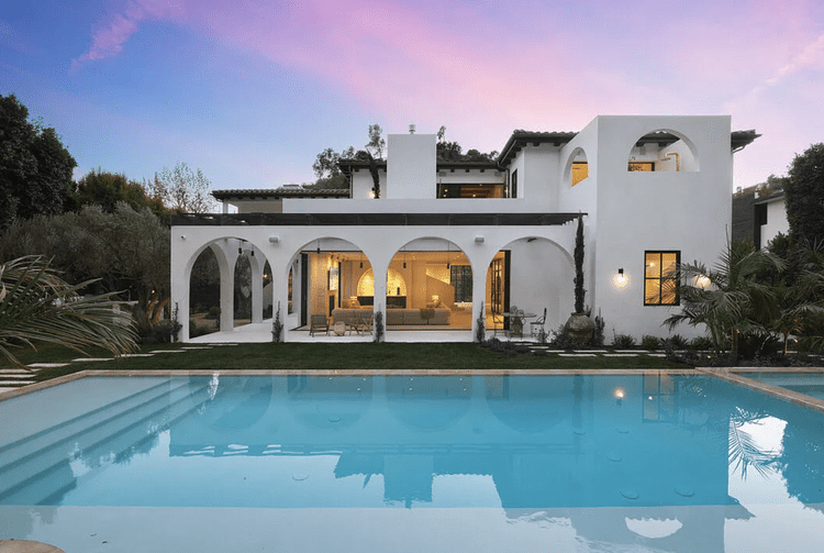White Spanish-modern home with arched loggia and pool at sunset