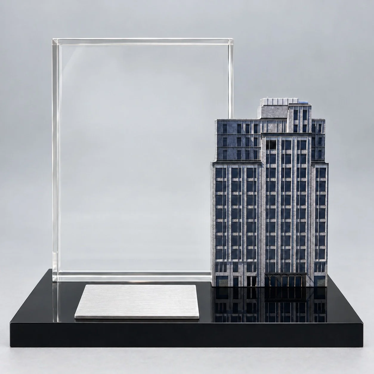 Detailed office tower model beside a clear panel on a black rectangular base.