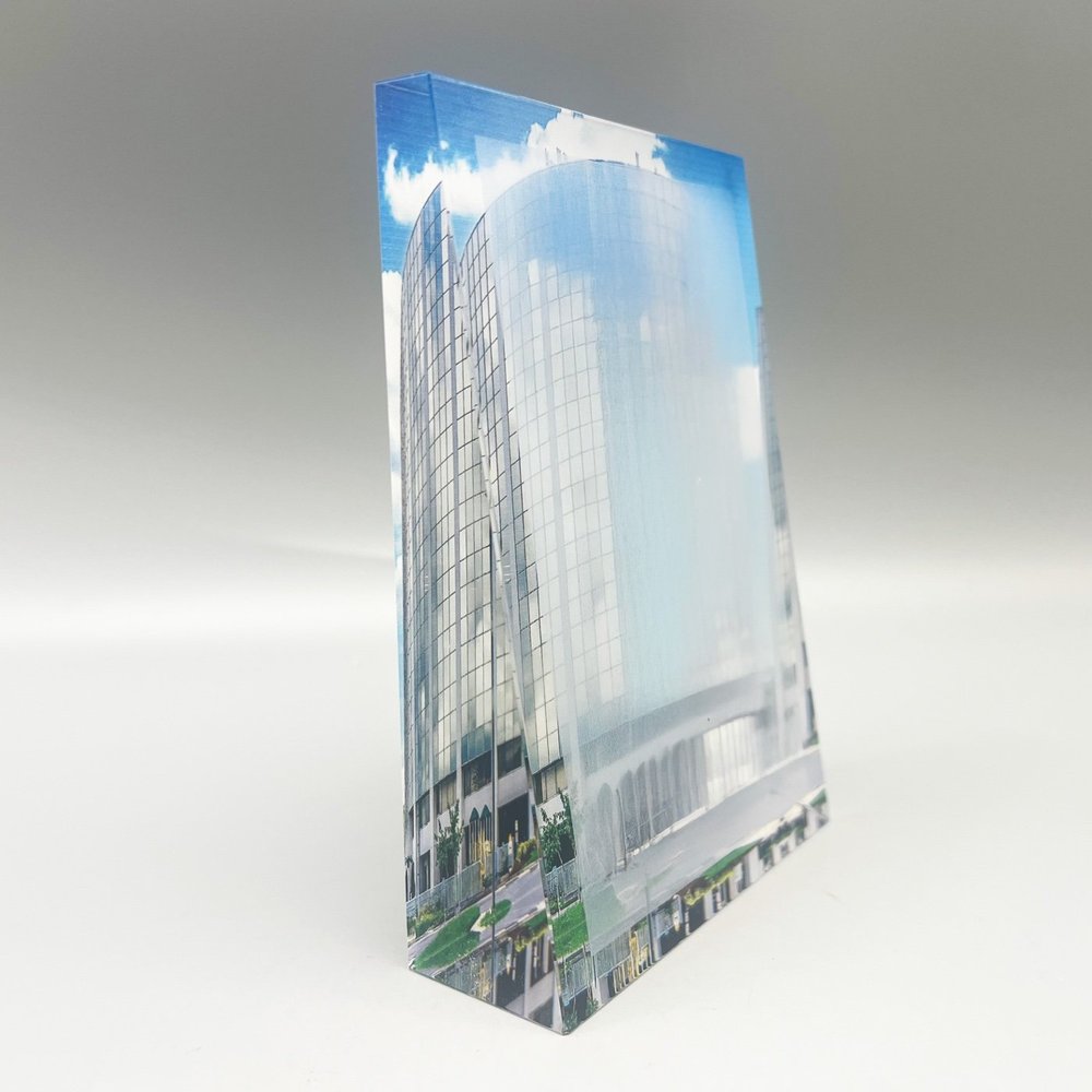 Clear rectangular deal toy displaying a photograph of a curved glass office tower.