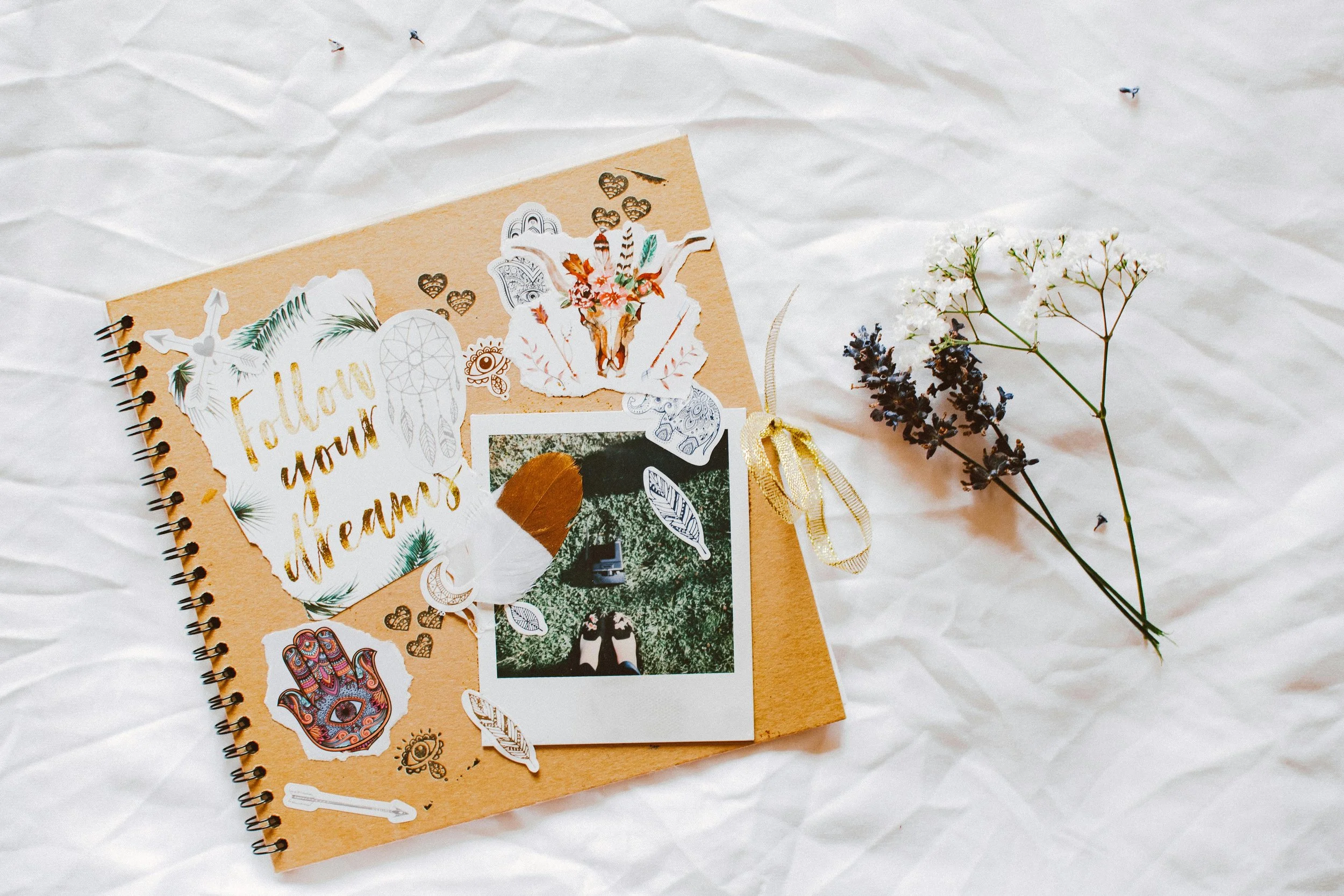 Scrapbook and loose flowers laying on a white textile