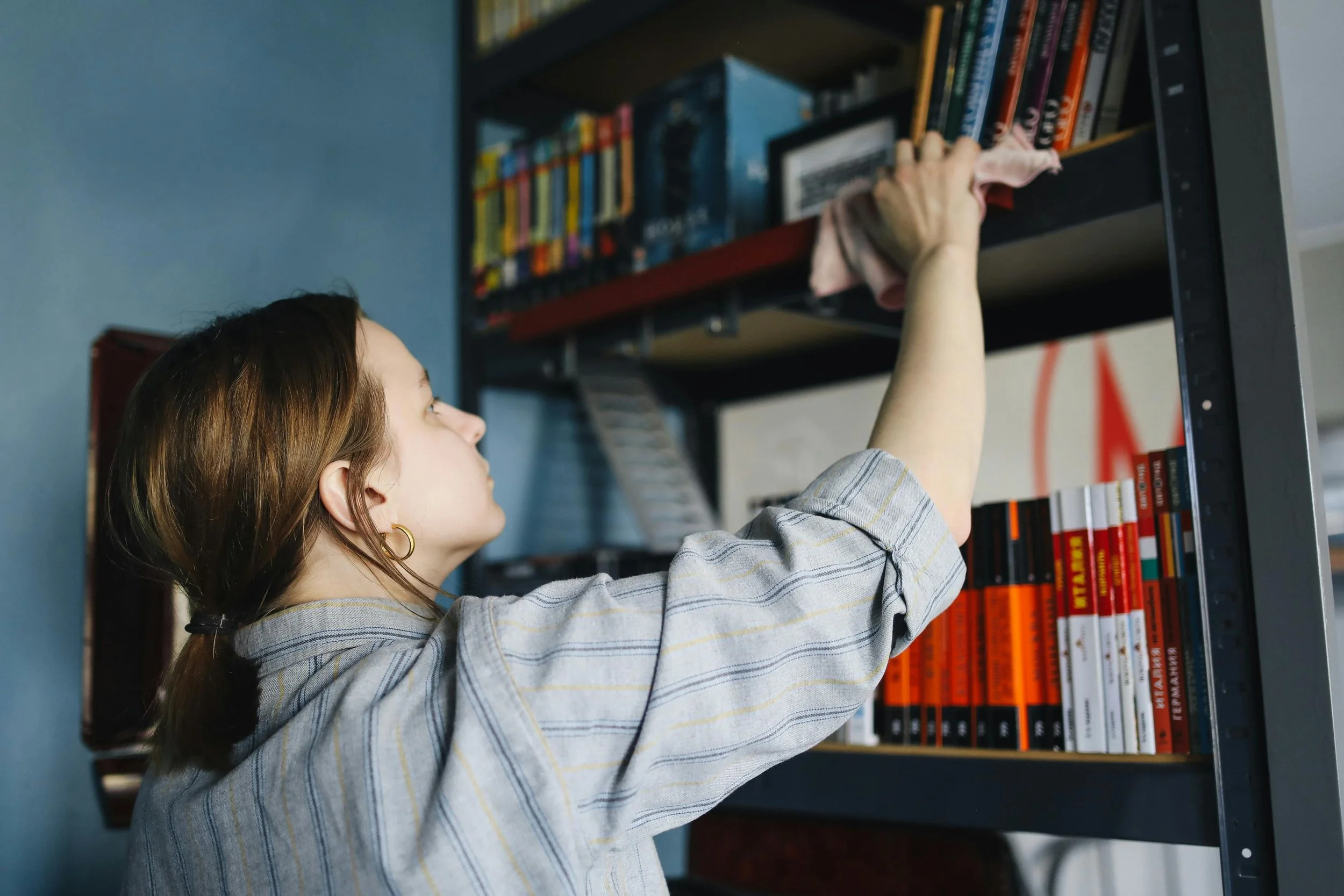 Woman organizing and dusting a shelf