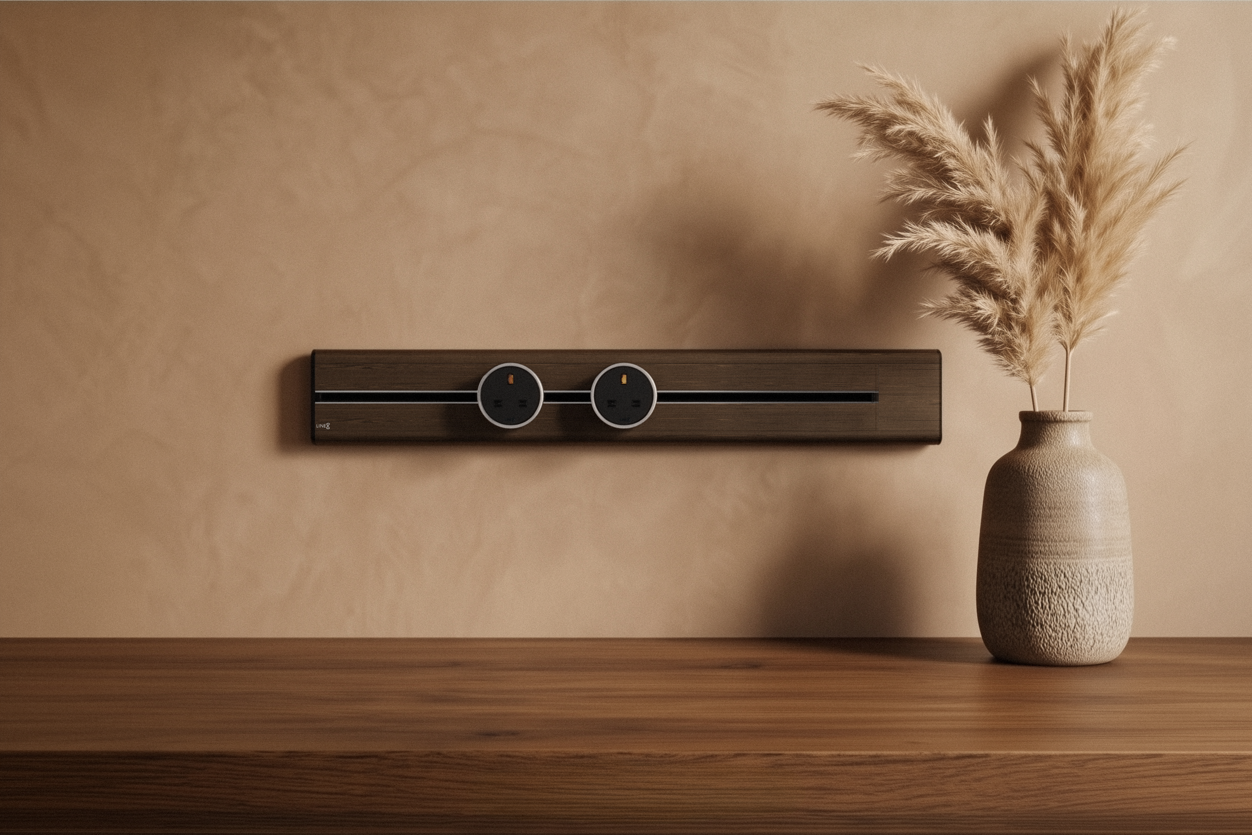 Premium Line8 Model SL electrical power track showcasing a rich Brazilian Rosewood finish. Mounted against a warm, textured earth-toned plaster wall, the high-end architectural fitting features a contrasting black center channel and two circular black power adaptors, positioned elegantly above a smooth natural wood surface and styled with a textured ceramic vase holding dried pampas grass.