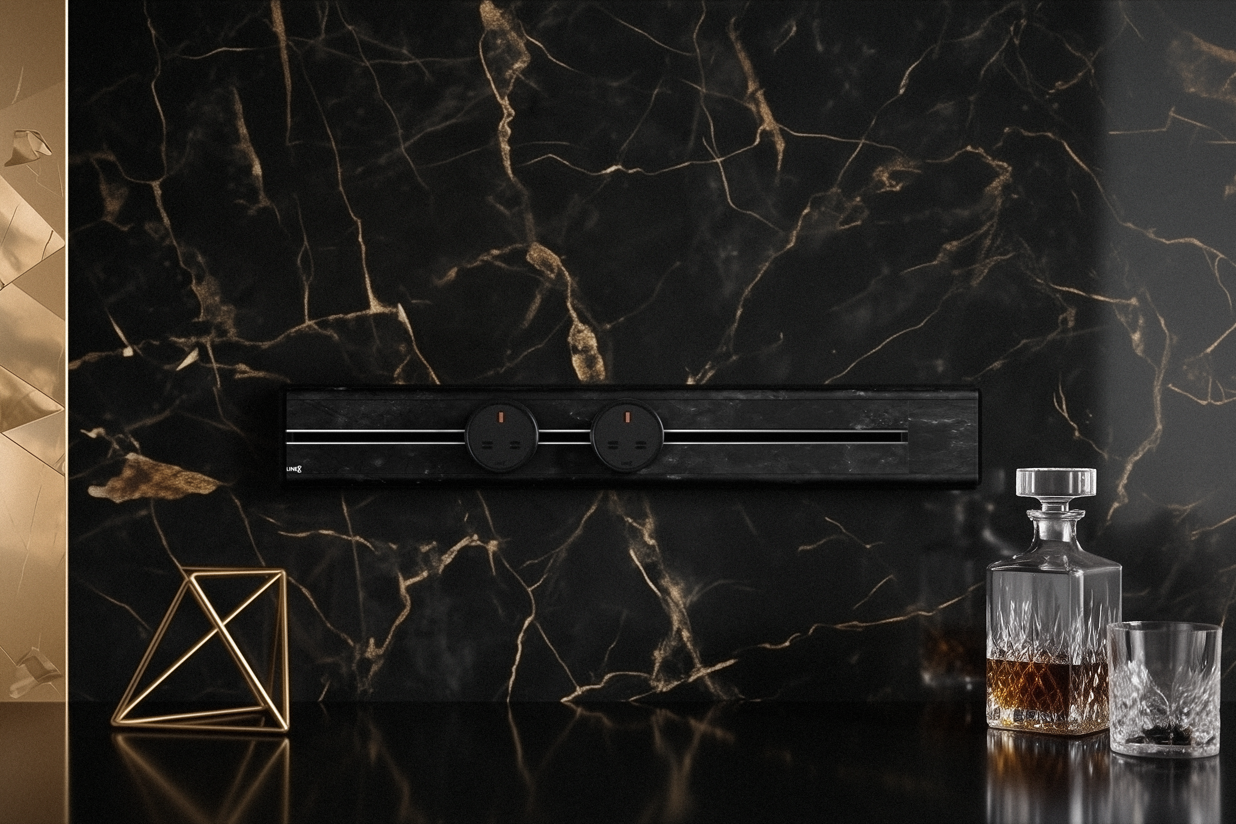 Premium Line8 Model SL electrical power track showcasing a luxurious Spanish Black Marble finish. Mounted against a dramatic, matching black marble wall with striking gold veining, the high-end architectural fitting features a sleek black center channel and includes two circular black power adaptors. The track seamlessly integrates above a highly reflective black countertop, elegantly styled with a gold geometric wire sculpture and a classic crystal decanter set.