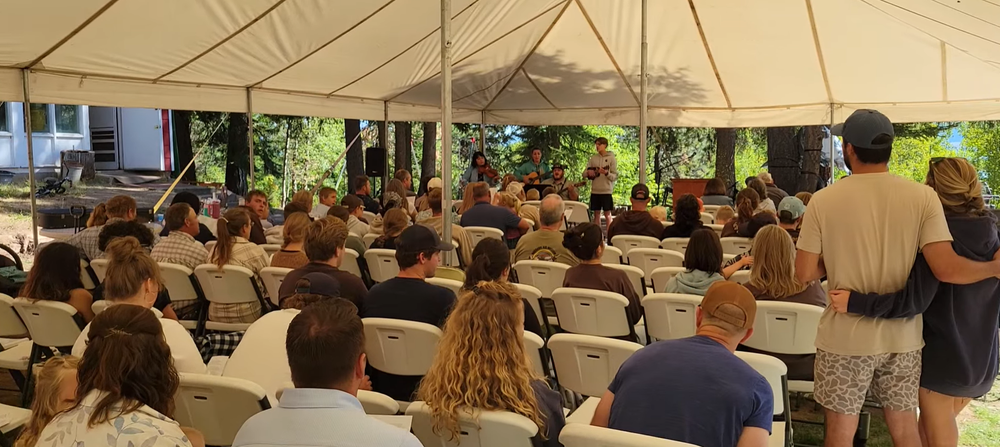 An outdoor gathering beneath a large tent.
