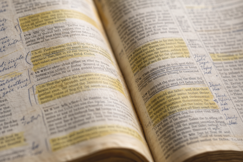Close-up of a well-used Bible with highlighted passages and handwritten margin notes