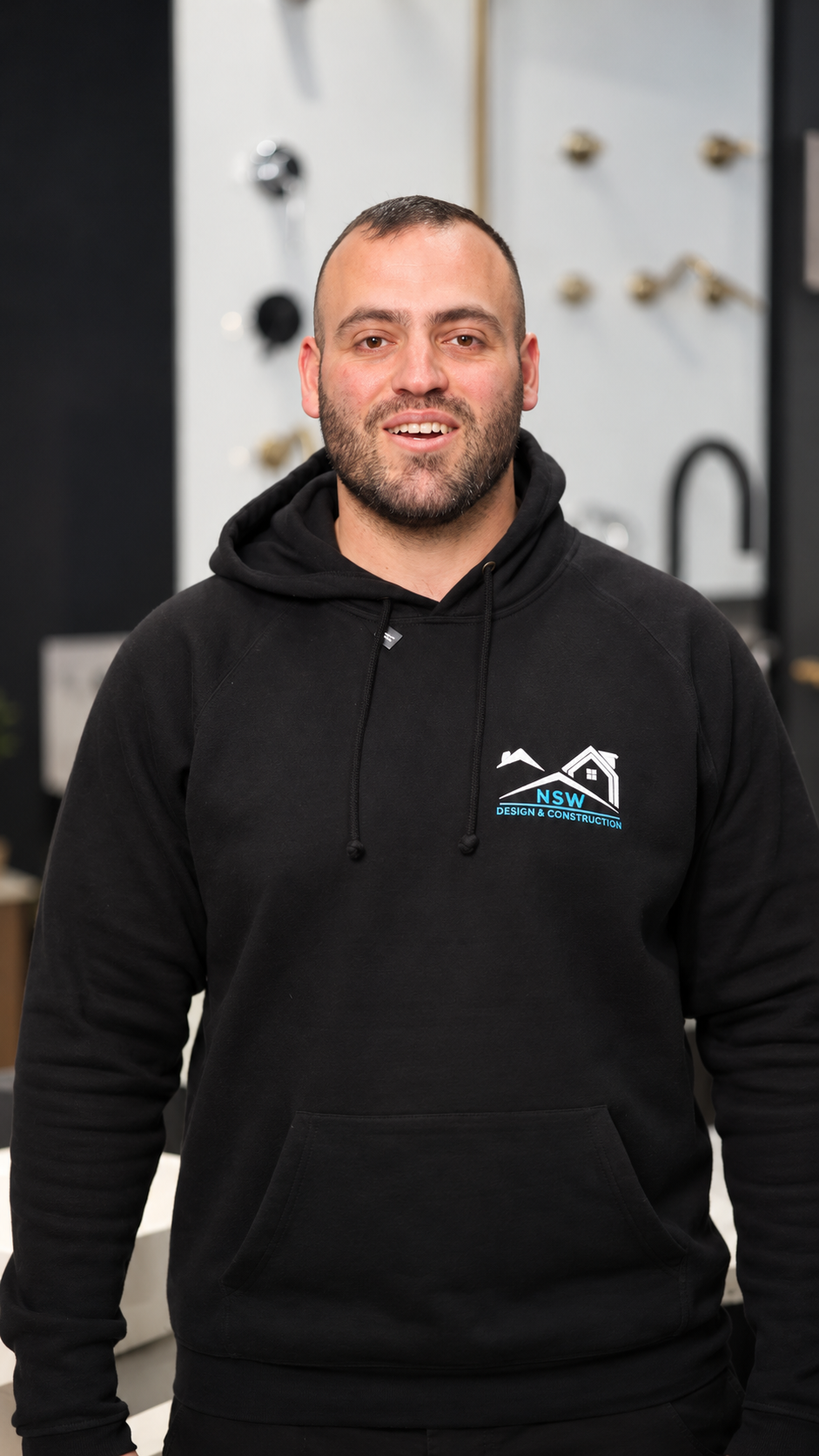 Anthony in a black NSW Design and Construction hoodie speaking to camera