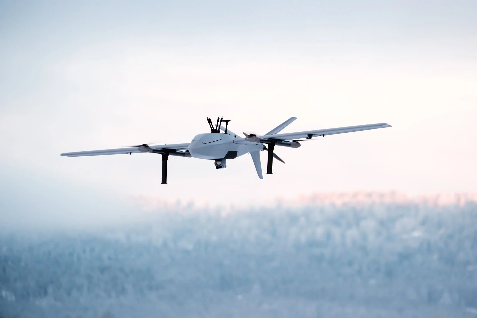 A Robot Aviation fixed-wing drone in flight against a cloudy sky.