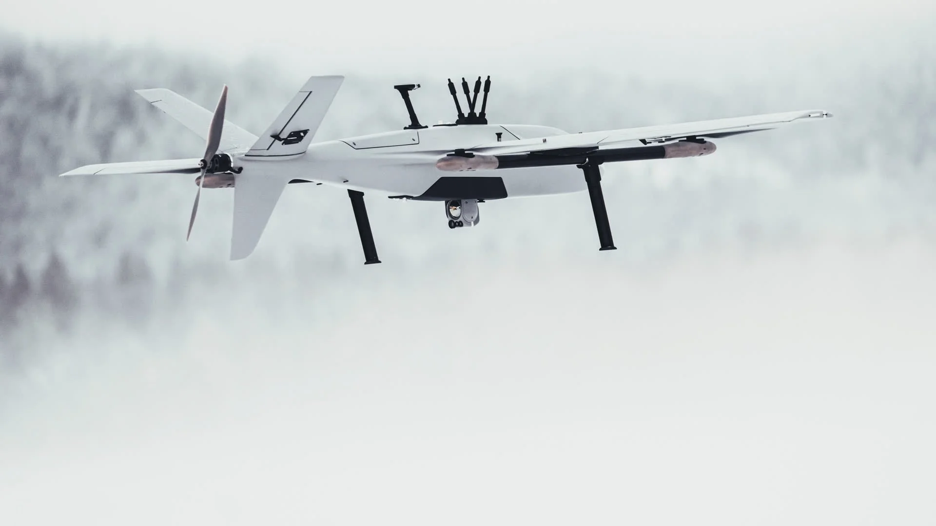 A Robot Aviation fixed-wing drone in flight through fog, showing its sensor payload.