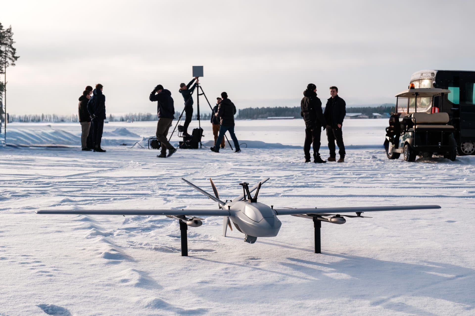 Robot Aviation team and film crew conducting a winter flight test of a fixed-wing drone on a snow-covered field.