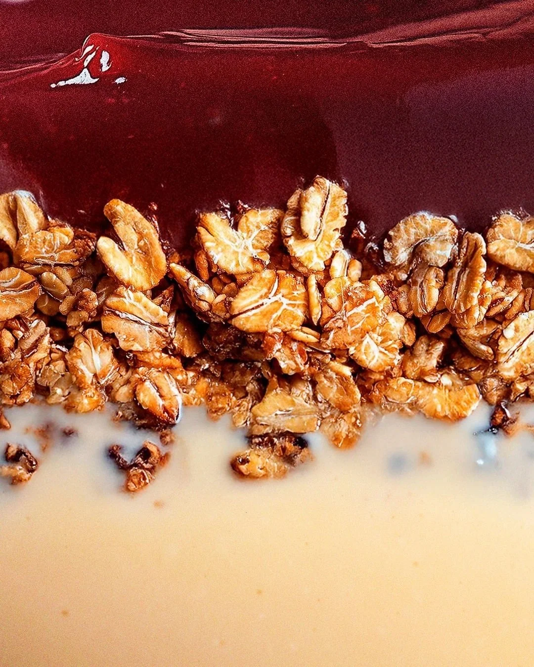 Açaí, granola and a creamy ingredient shown in a macro photograph.