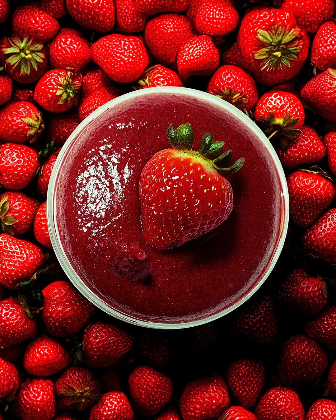 Top view of an açaí bowl topped with a strawberry, surrounded by fresh strawberries.