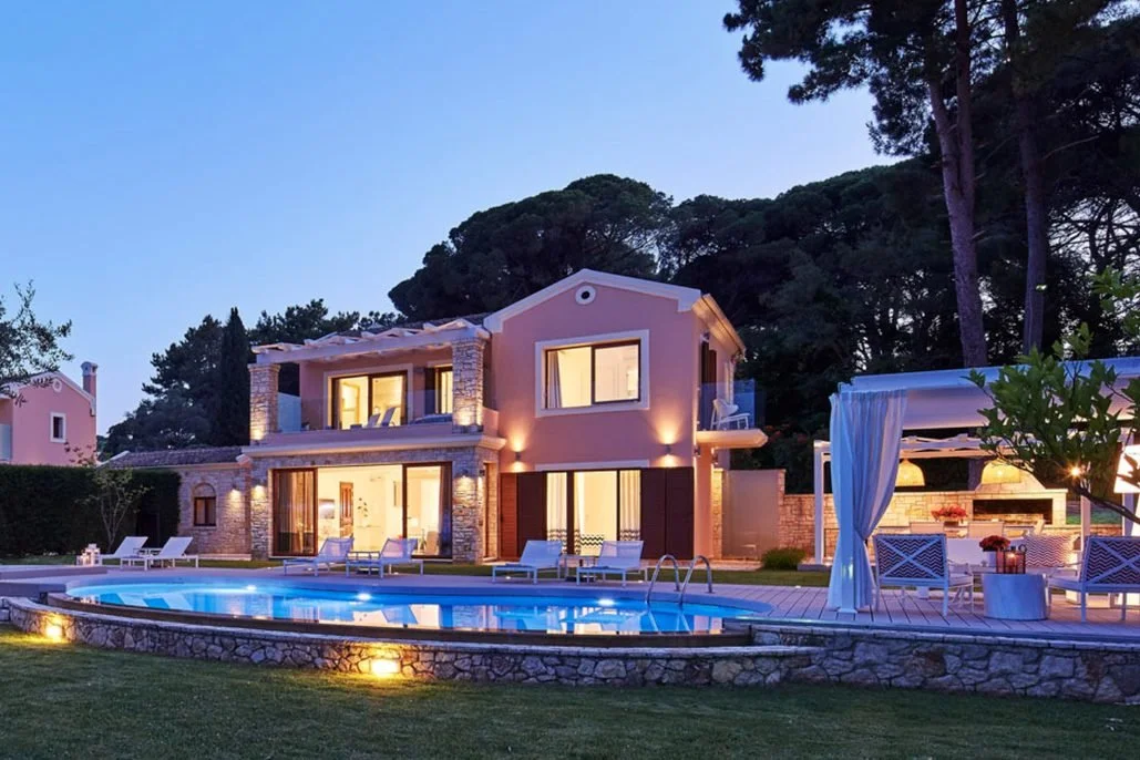 The Deluxe Three Bedroom Villa at dusk, a two-storey villa lit up behind its private pool and garden