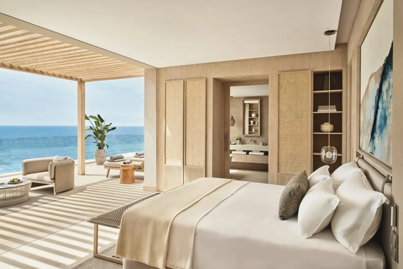 A bedroom in the Deluxe Two Bedroom Grand Penthouse Suite opening onto a covered terrace above the sea