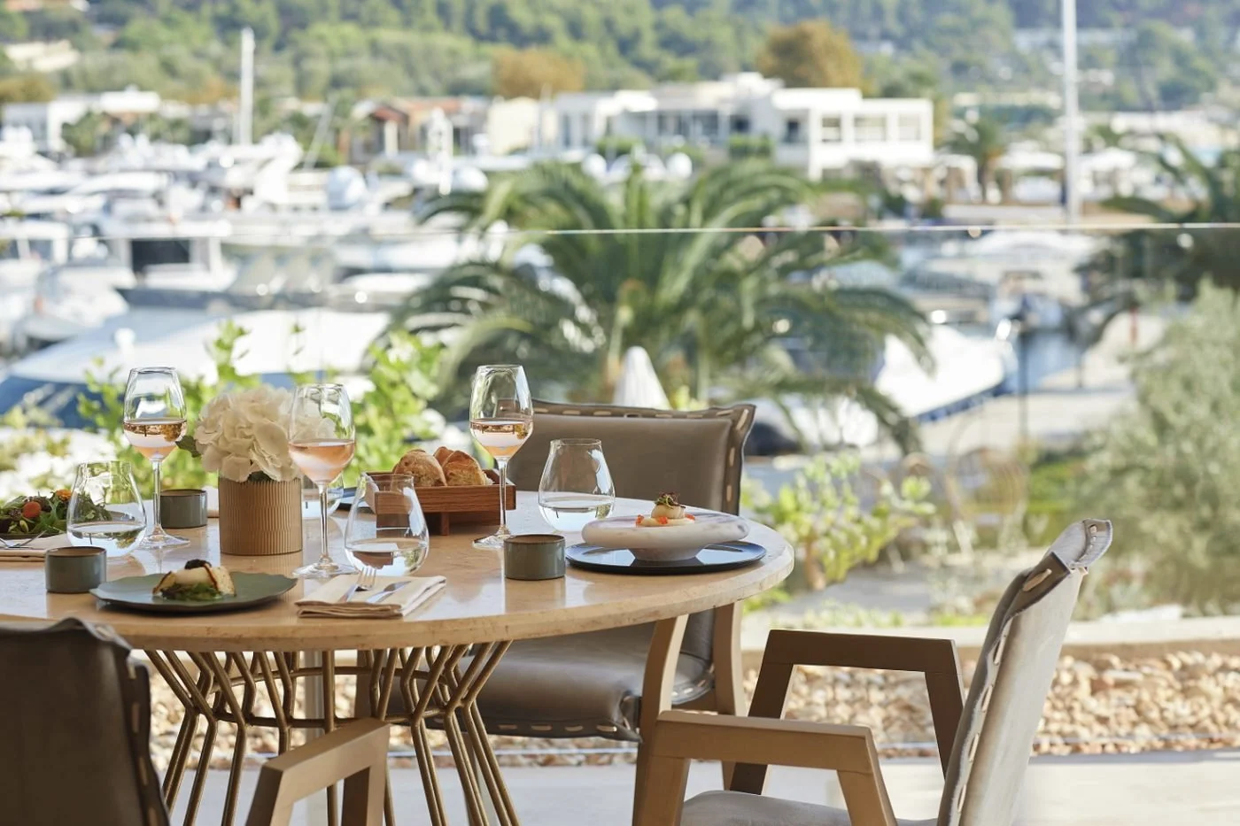 A table set for lunch at Water, with glasses of rosé and the yachts of Sani Marina beyond