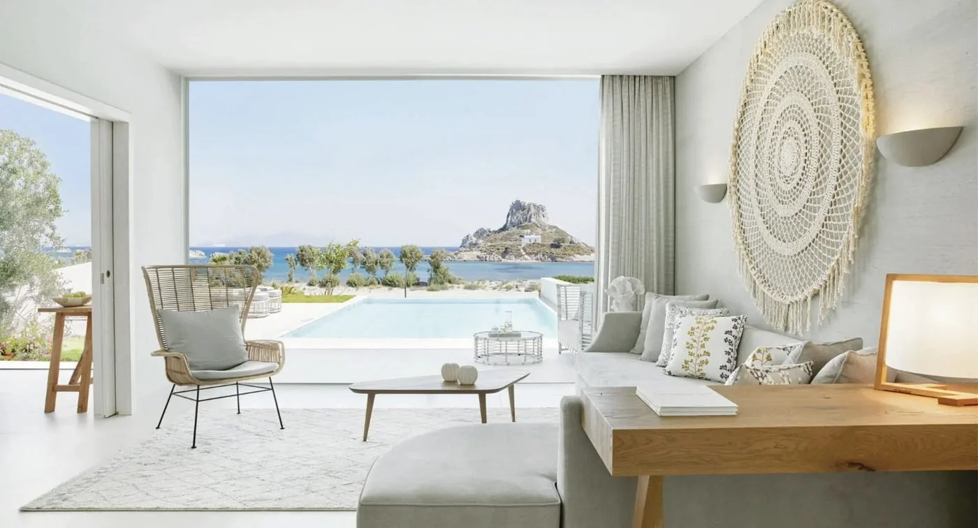 A Deluxe One Bedroom Bungalow Suite at Ikos Aria opening onto its private pool, with Kastri island beyond
