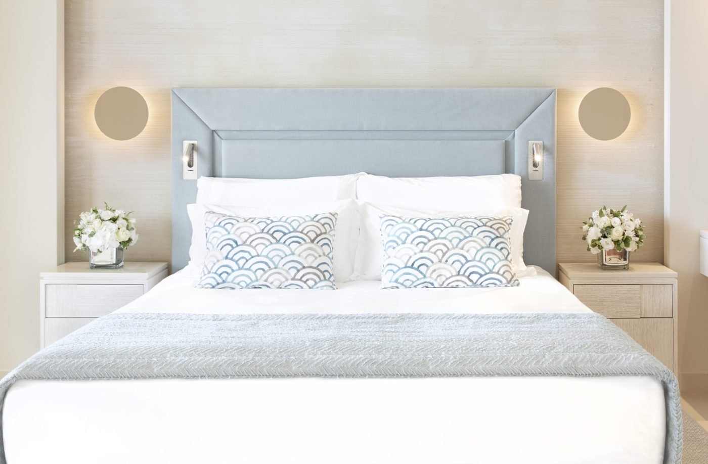 The bed in a Deluxe Junior Suite Private Garden, with crisp white linen and patterned cushions