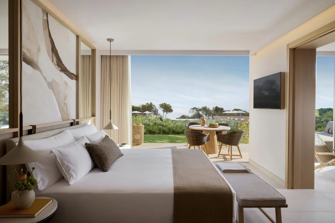 A One Bedroom Suite bedroom opening onto a garden terrace with a dining table