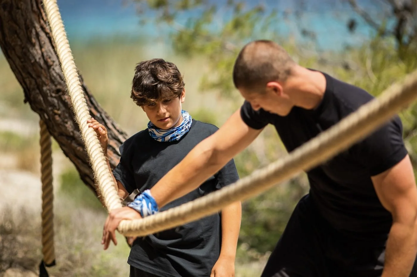 A boy tackling a rope course with an instructor at the Bear Grylls Survival Academy at Sani