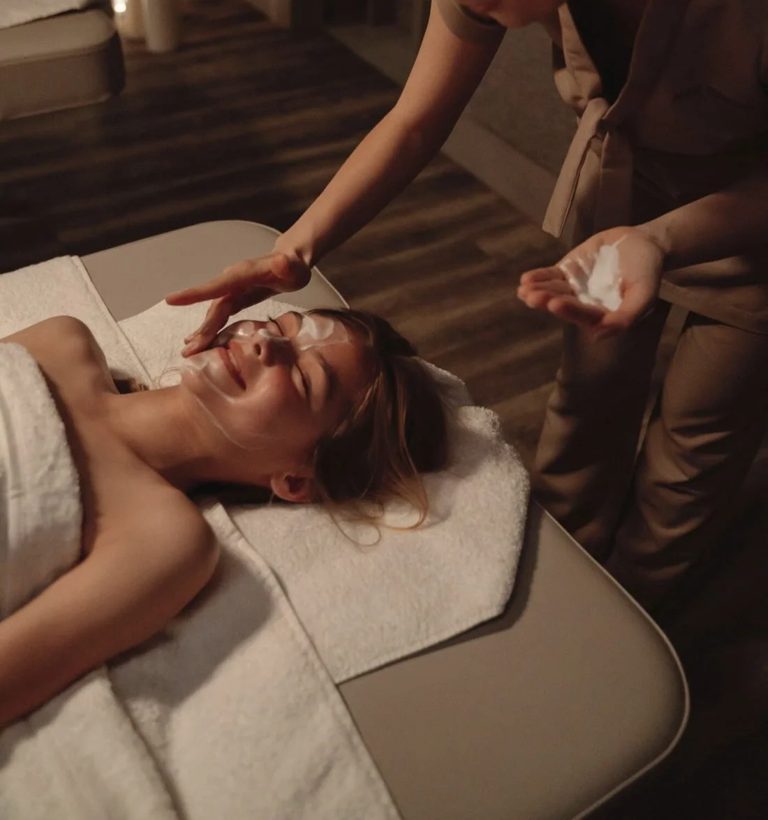 A therapist applying a facial treatment to a guest lying on a spa bed
