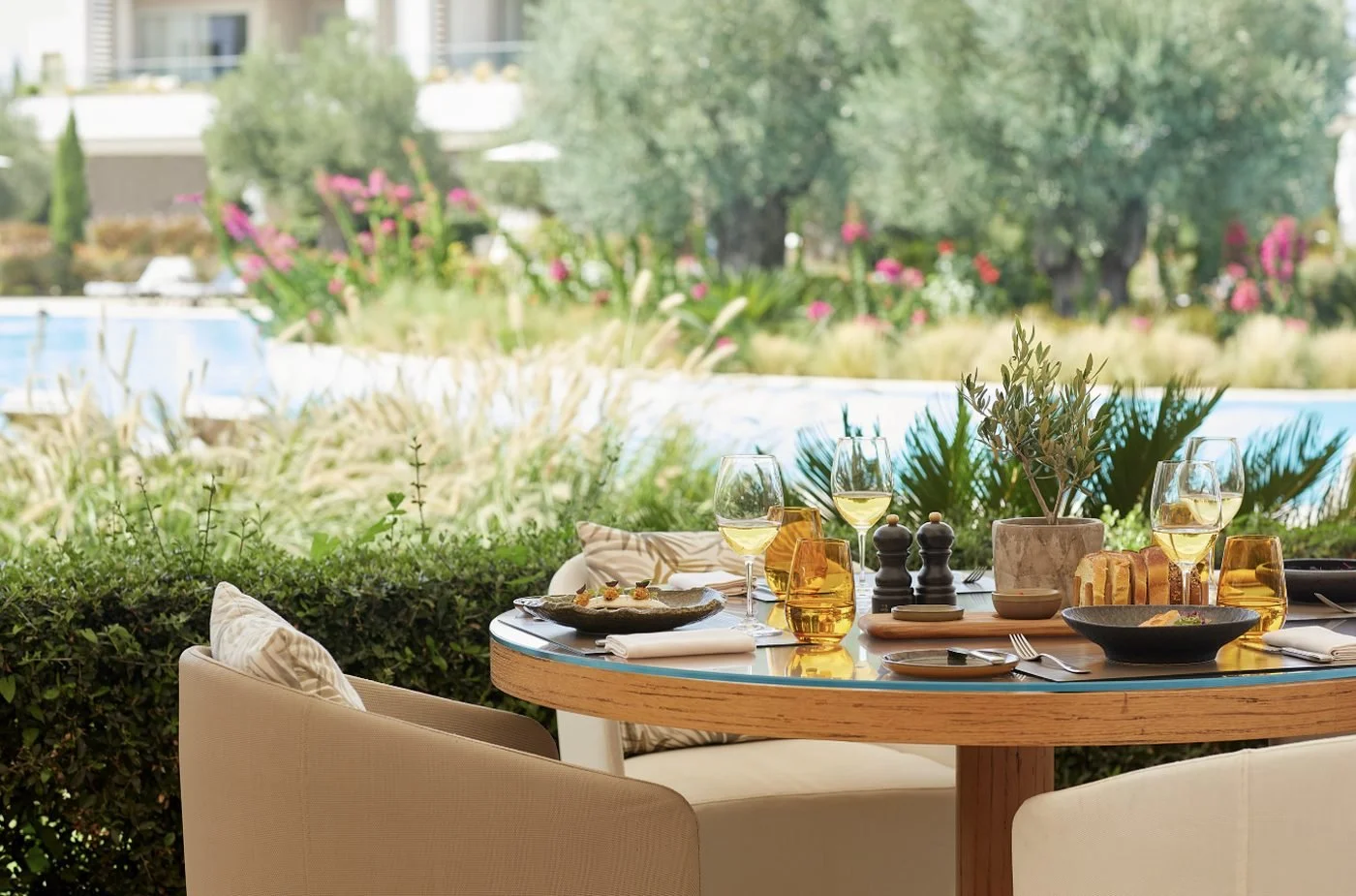 A table laid on the terrace at The Market, among flowering gardens beside the pool