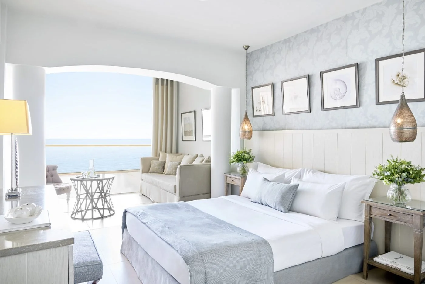 A Junior Suite at Sani Beach with a seating corner and a sea view through an arched opening