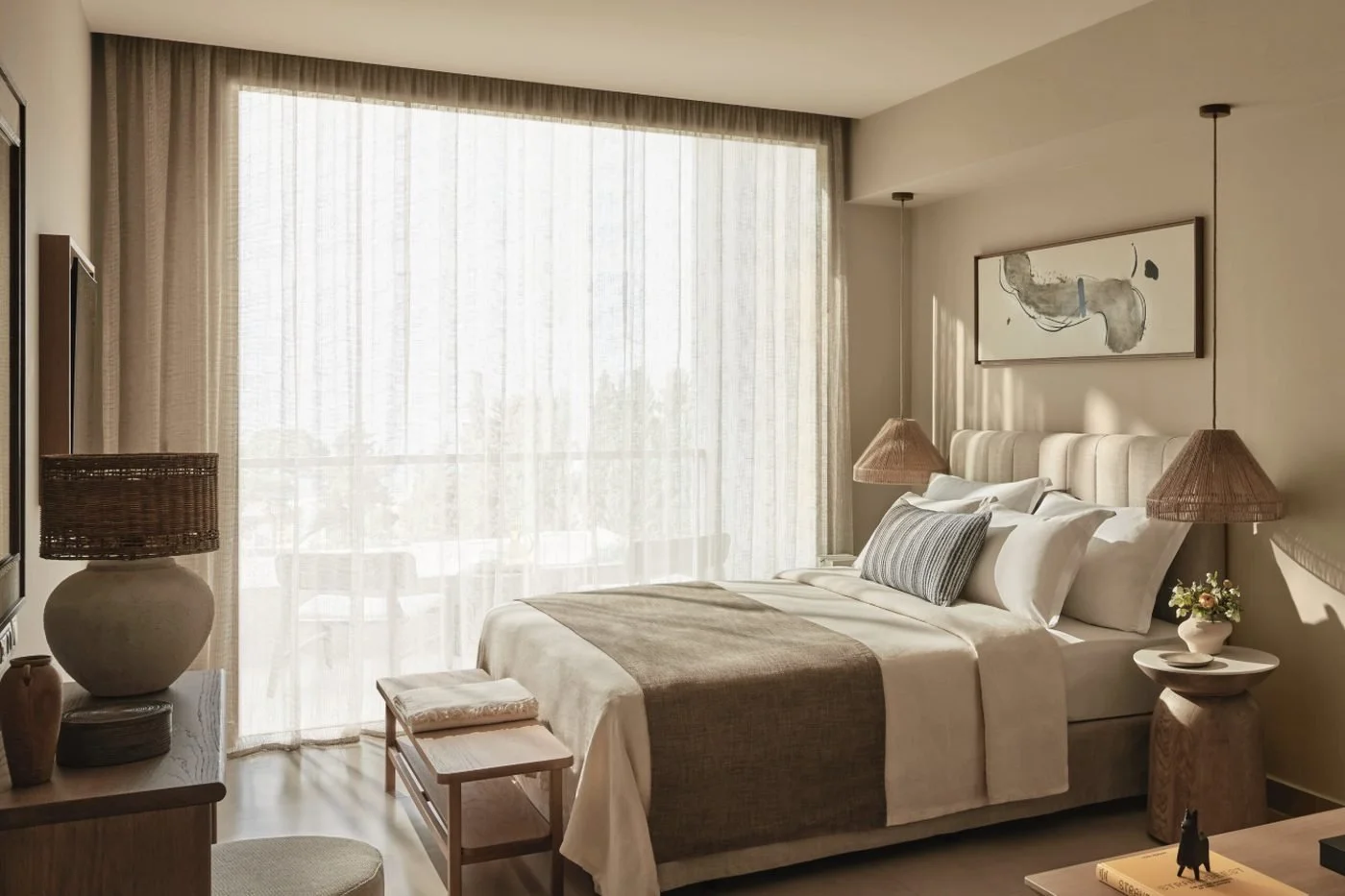 A Double Room at Ikos Olivia in mocha and ivory tones, with sheer curtains drawn across the balcony doors