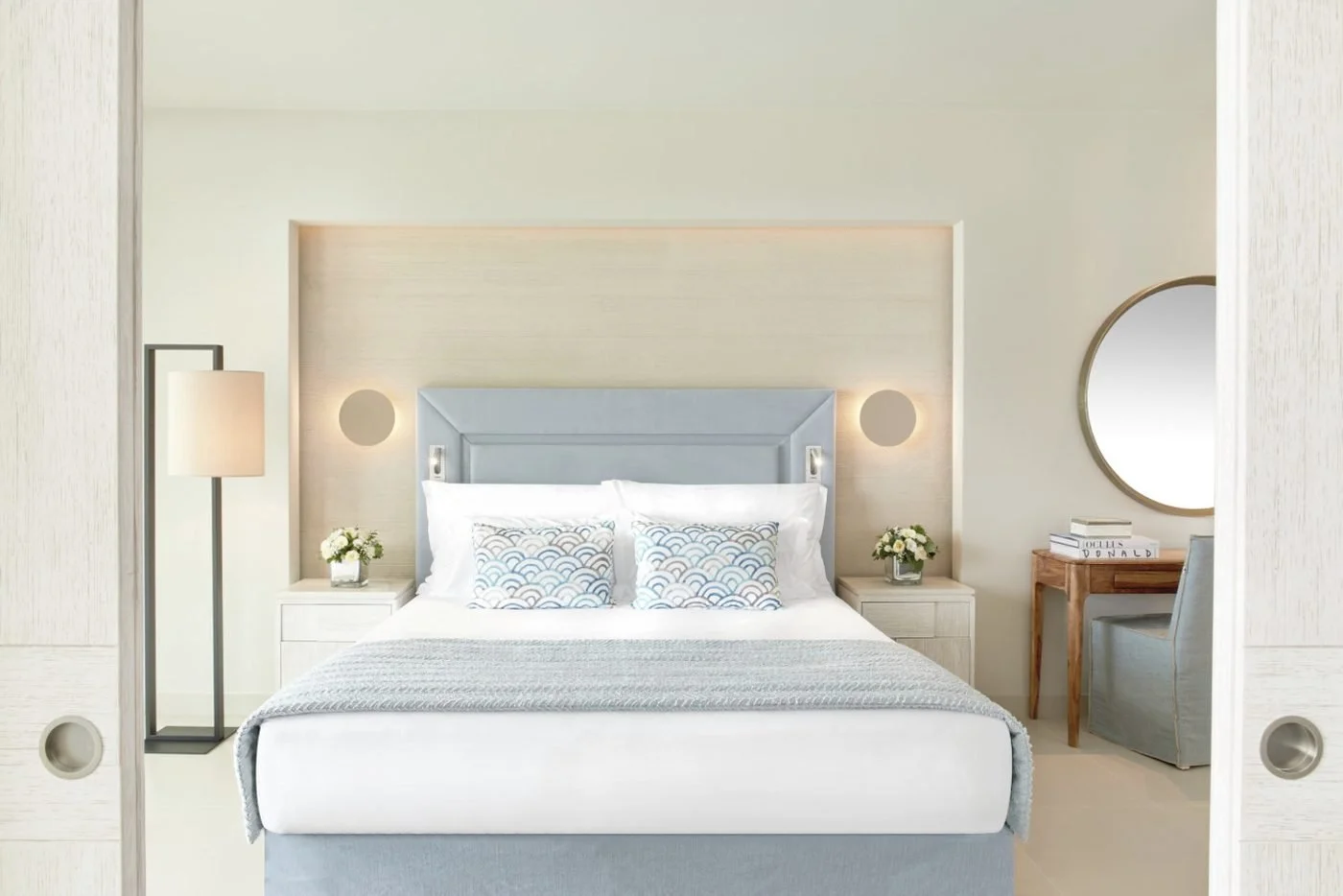 A bedroom in a Deluxe Two Bedroom Suite, seen through open sliding doors, in soft grey and blue