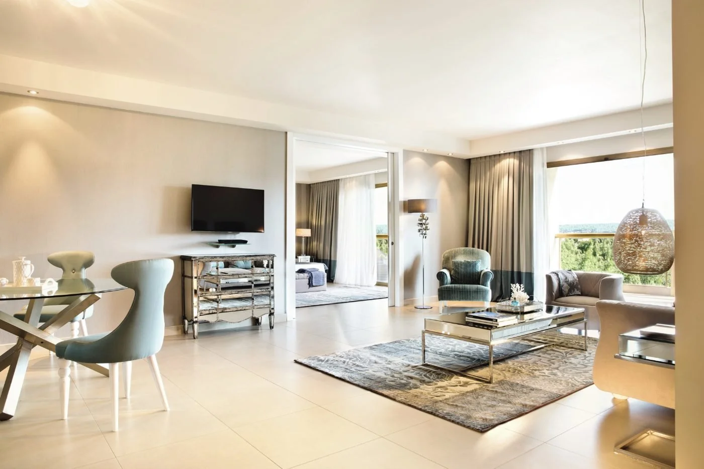The living and dining area of a Deluxe Two Bedroom Family Suite, with a bedroom through sliding doors